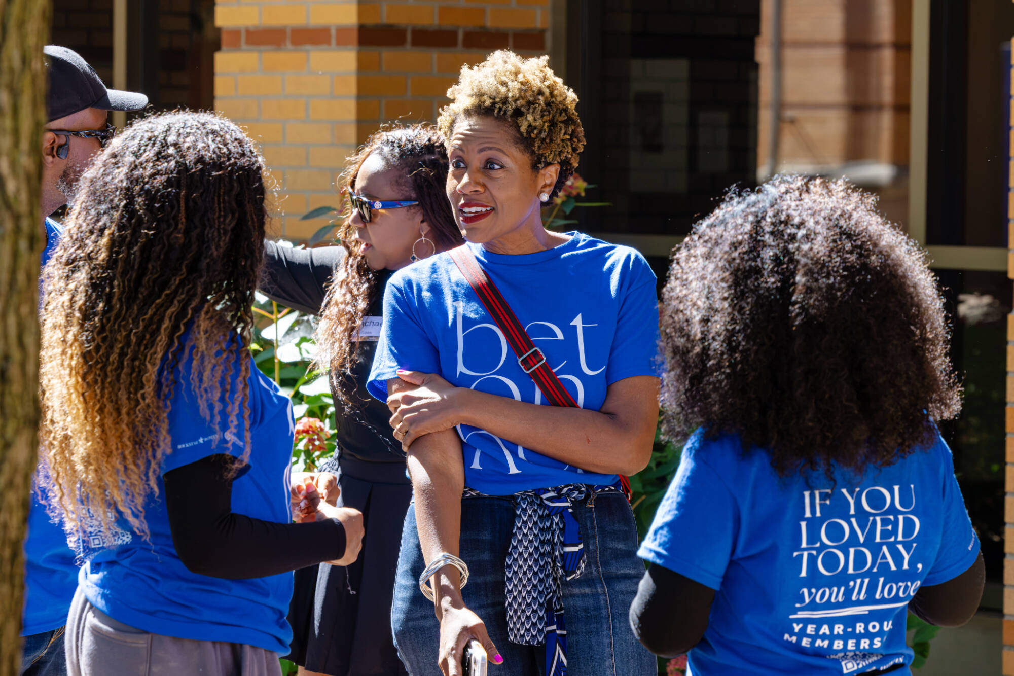 Shannon Cohen is in center in a blue t-shirt speaking to two students in the same blue t-shirt